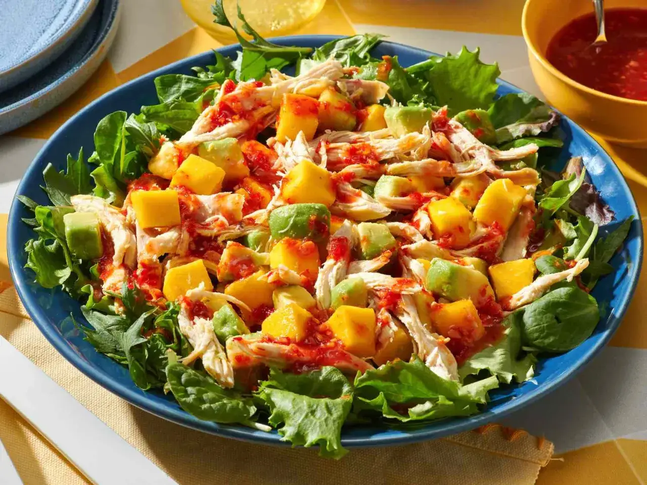 Kolorowa sałatka z kurczakiem, awokado i kostkami mango, polana pikantnym sosem. Idealna na letni obiad.