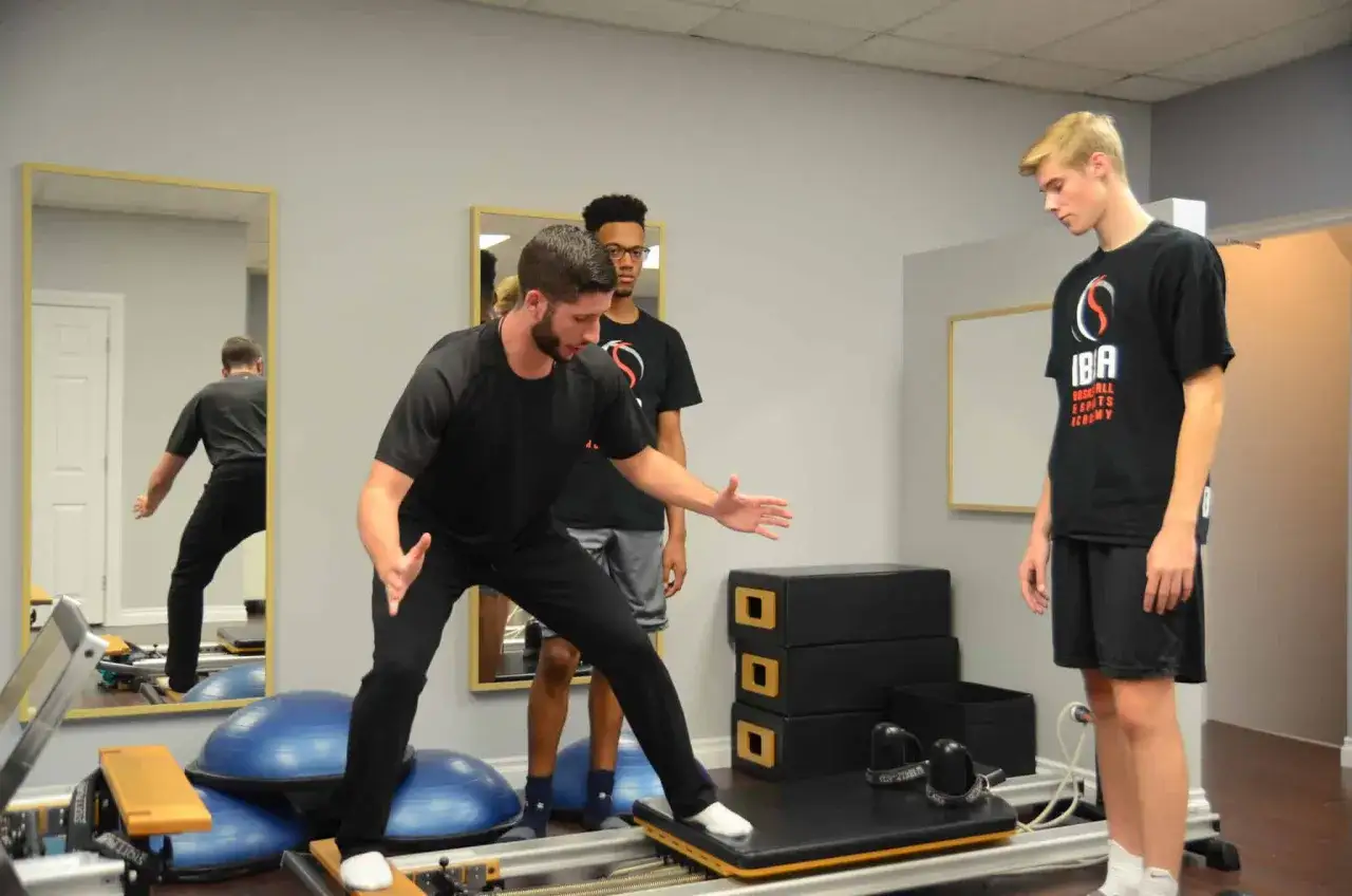 Un entra&icirc;neur guide un jeune joueur de basket dans sa pr&eacute;paration physique, ax&eacute;e sur l'&eacute;quilibre et la force.