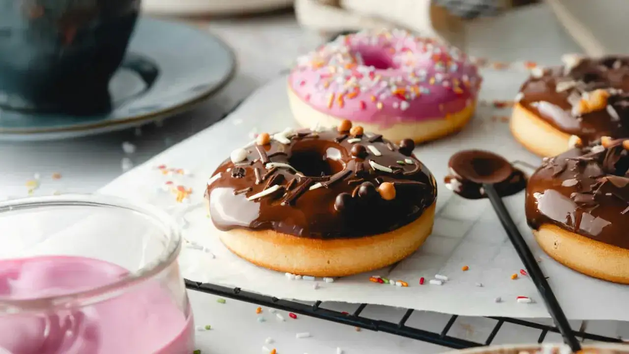 Leckere Donuts mit Schokoglasur und bunten Streuseln, perfekt f&uuml;r ein selbstgemachtes Donuts Rezept aus dem Backofen.