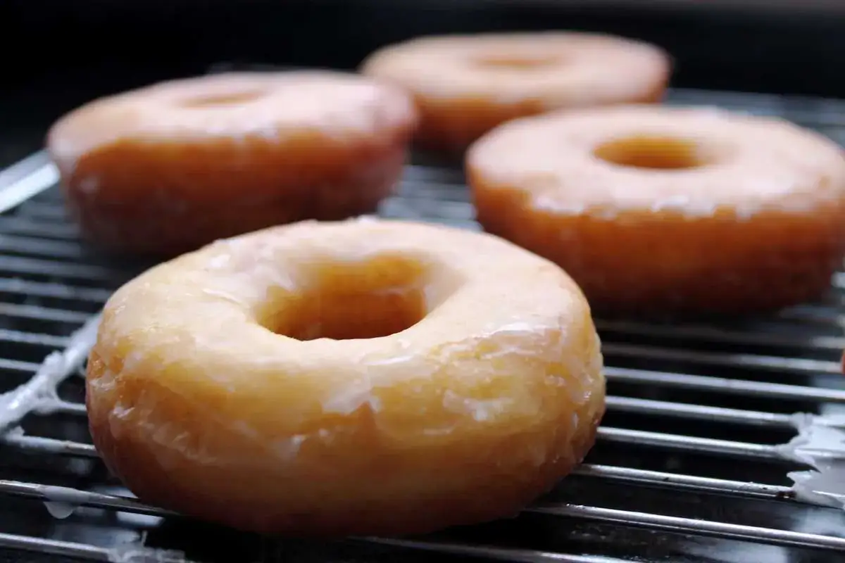 Cuatro donuts glaseados sobre una rejilla, listos para disfrutar. Una deliciosa receta de donuts caseros.