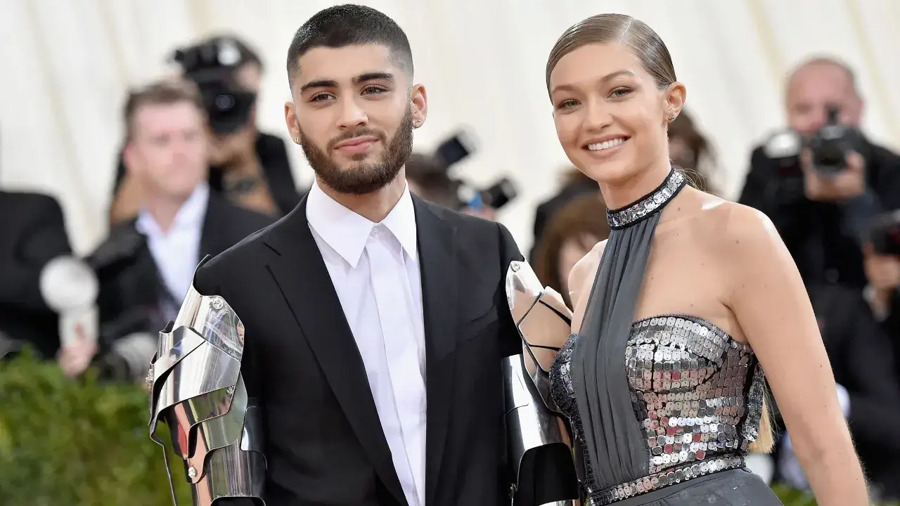 Zayn Malik i Gigi Hadid na czerwonym dywanie, on w czarnym garniturze i metalowych naramiennikach, ona w błyszczącej sukni.