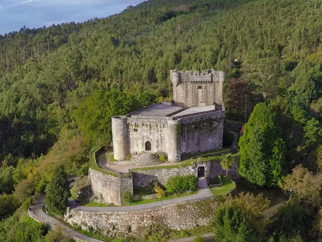 El Castelo de Sobroso, una fortaleza de piedra, se alza majestuoso entre la frondosa vegetación de una colina boscosa.