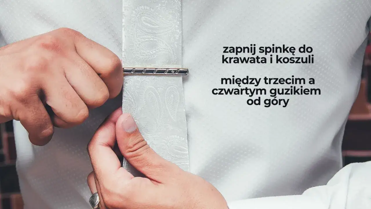 Mężczyzna zapina spinkę do krawata i koszuli między trzecim a czwartym guzikiem od g&oacute;ry. Elegancki spos&oacute;b, jak nosić spinkę do krawata.