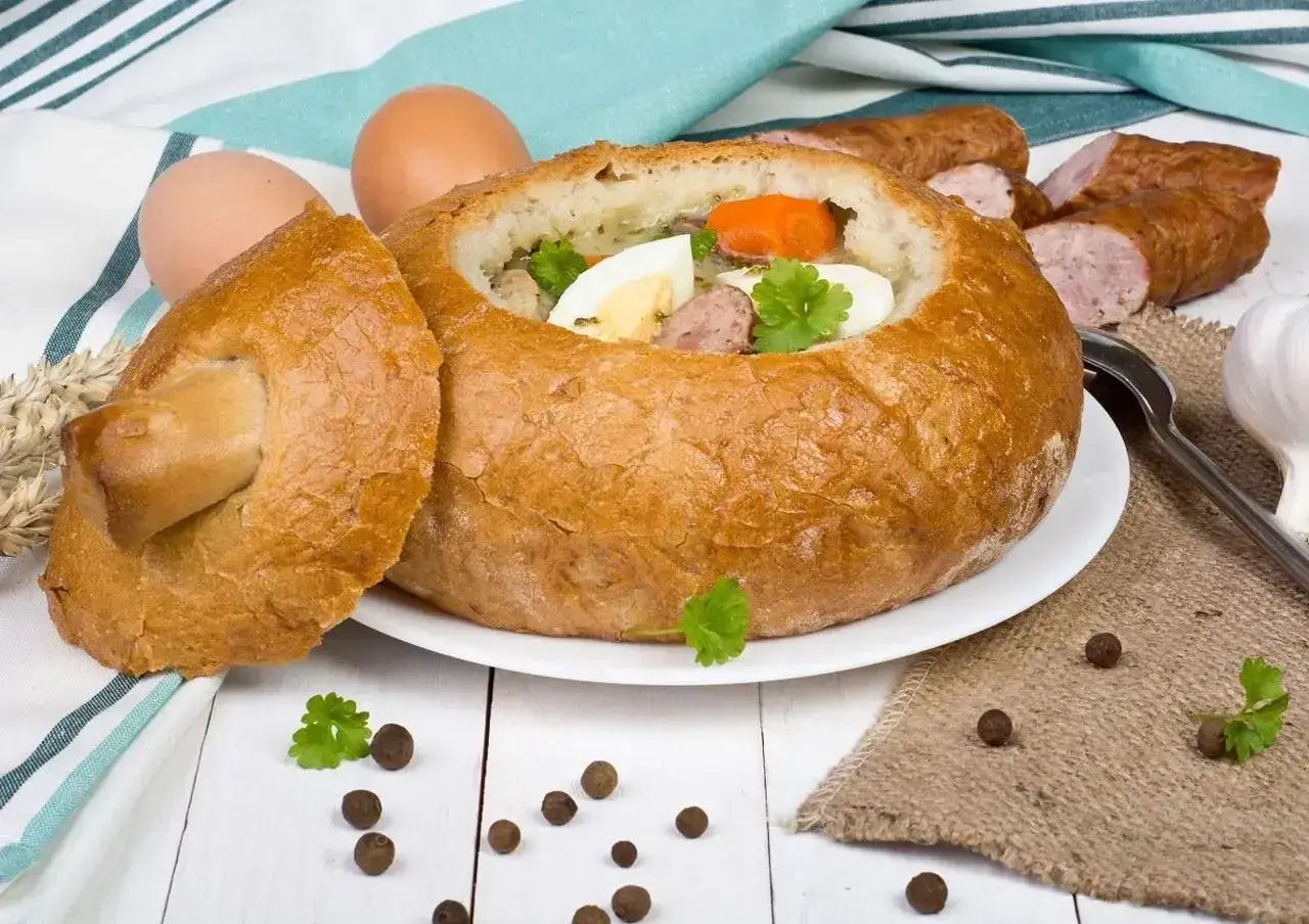 Pyszny żurek w chlebie, podany z jajkiem i kiełbasą. Idealny na polski obiad.