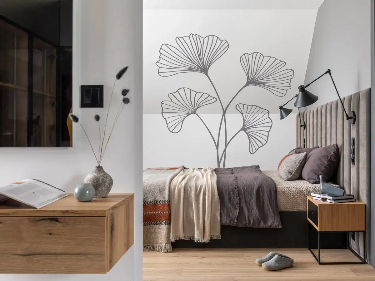 Moderne schlafzimmer wand ideen mit Ginkoblatt-Aufkleber. Ein gem&uuml;tliches Bett mit Kissen und Decken, Nachttisch und Wandlampen.