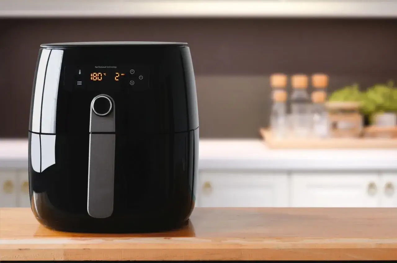 Czarny air fryer na drewnianym blacie. Idealny wybór, gdy zastanawiasz się, jaki air fryer wybrać do swojej kuchni.