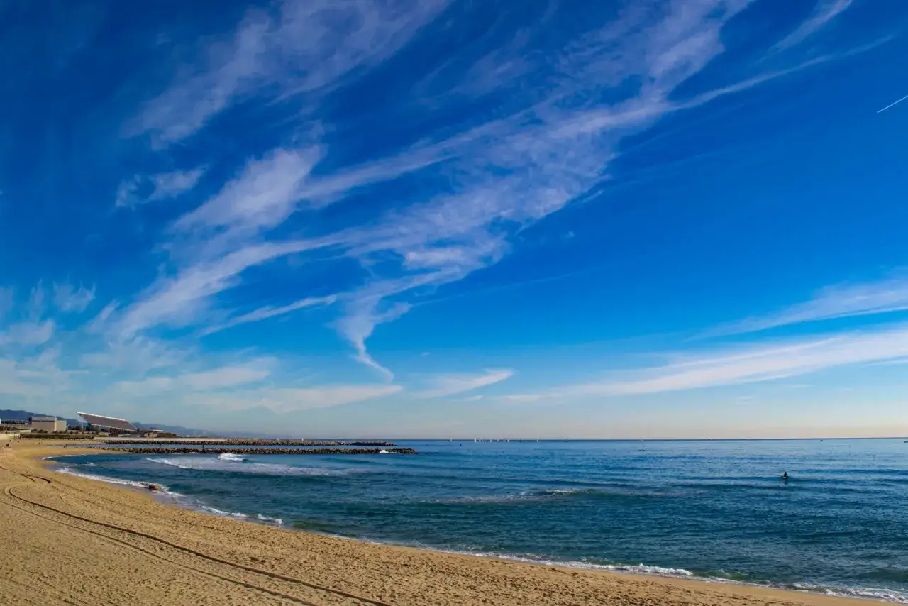 Piasek, fale i błękitne niebo nad morzem. Czy Barcelona ma morze? Tak, to jej plaża!