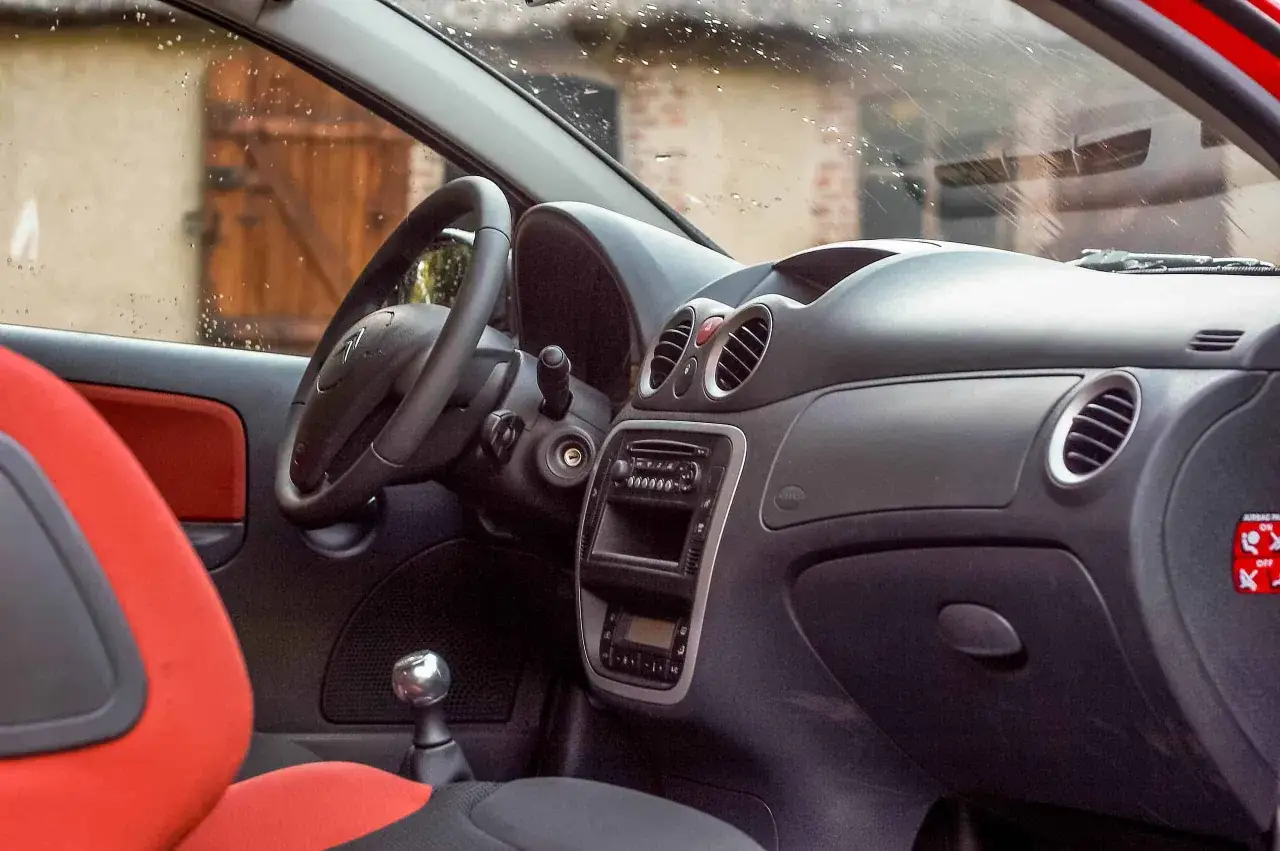 Wnętrze Citroëna c2 z czerwonymi akcentami na siedzeniach i czarną deską rozdzielczą.