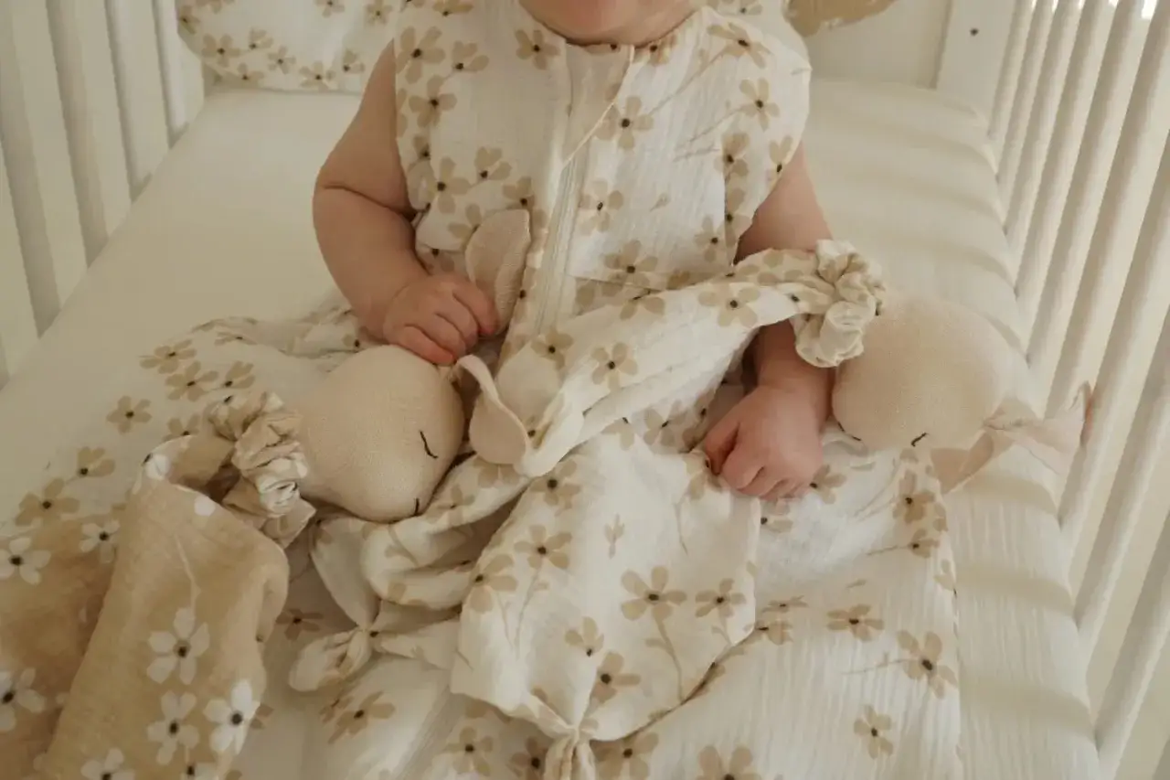 B&eacute;b&eacute; dans son lit, entour&eacute; de doudous et d'une gigoteuse &agrave; fleurs. La question du lit b&eacute;b&eacute; jusqu'&agrave; quel &acirc;ge est souvent pos&eacute;e par les parents.