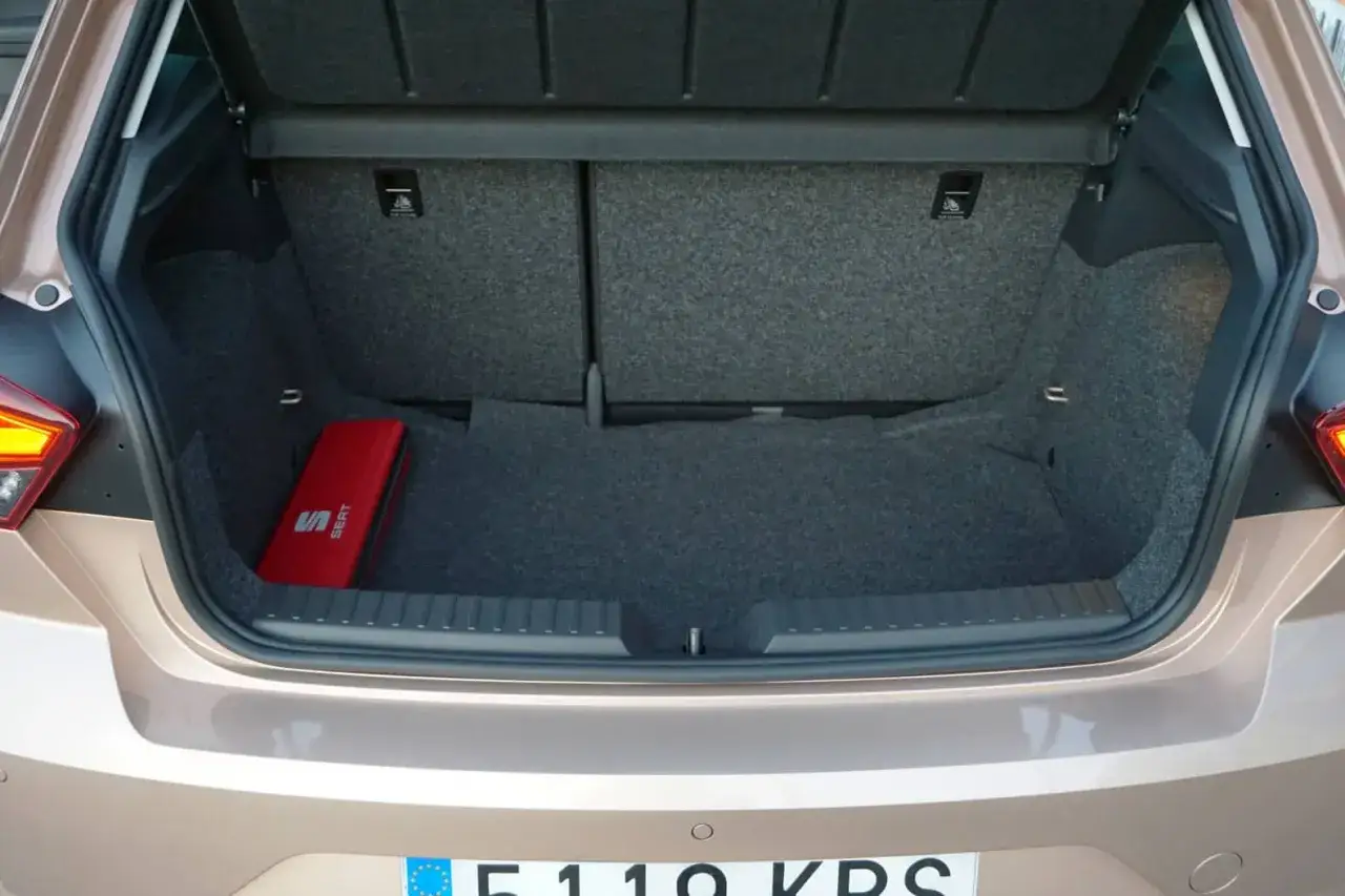 Maletero abierto de un Seat Ibiza, mostrando su espacio y un botiqu&iacute;n rojo. La capacidad del maletero es ideal para escapadas.