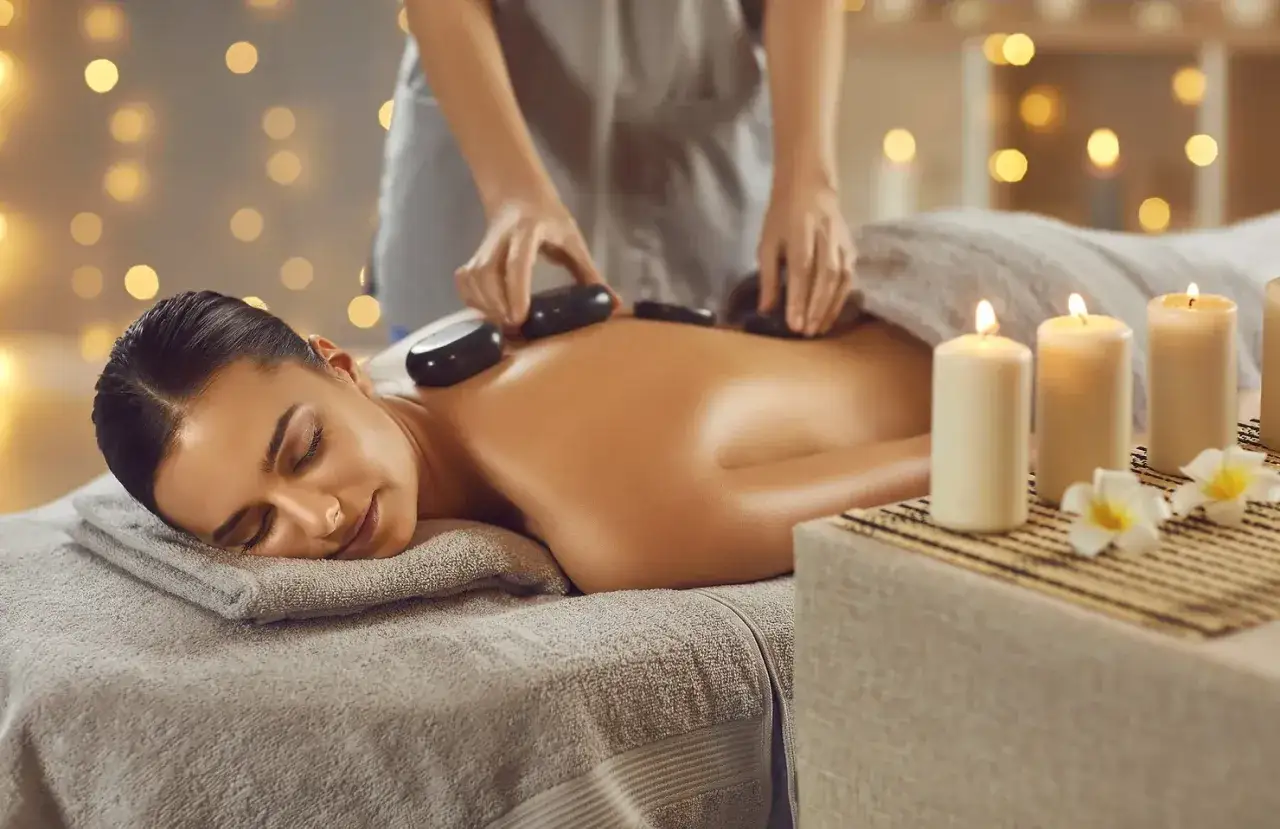 Relaks w spa: masaż gorącymi kamieniami na plecach, przy świecach i kwiatach.