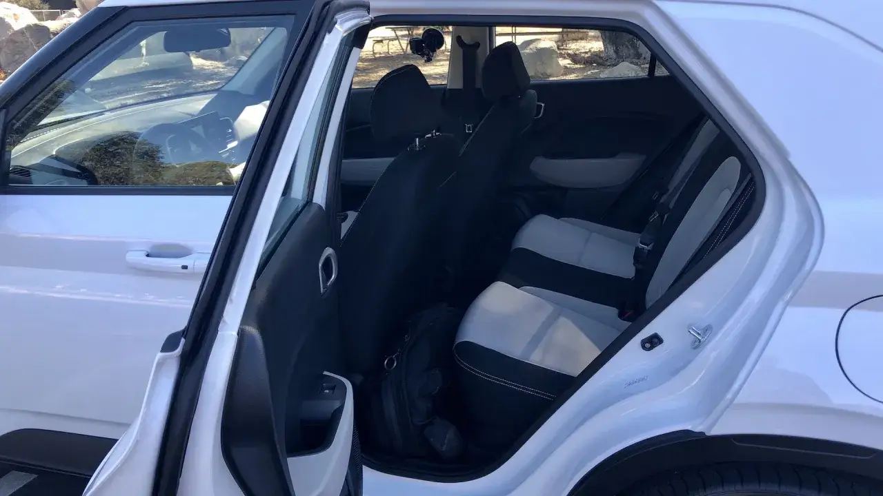Wnętrze białego Hyundai Venue z czarnymi i szarymi siedzeniami. Na podłodze leży czarna torba.