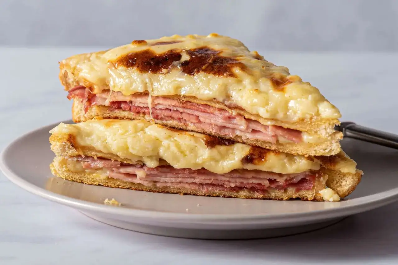 En gyllene croque monsieur staplad på en annan, med smält ost och skinka.