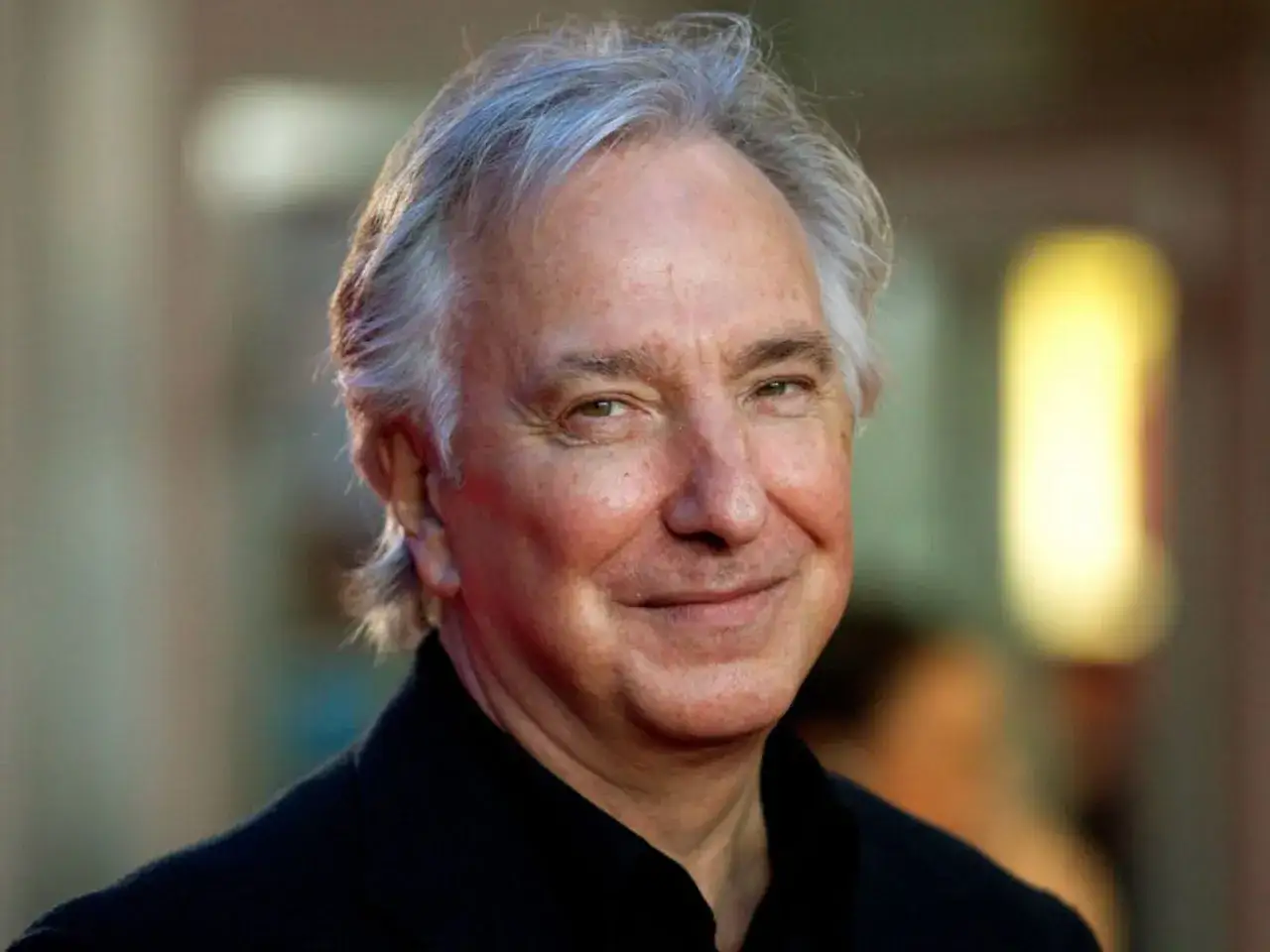 Alan Rickman, skådespelaren som spelade Severus Snape, ler mot kameran.