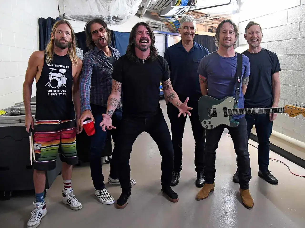 Les membres de Foo Fighters posent ensemble, prêts pour le spectacle. L'un tient une guitare, un autre des baguettes.