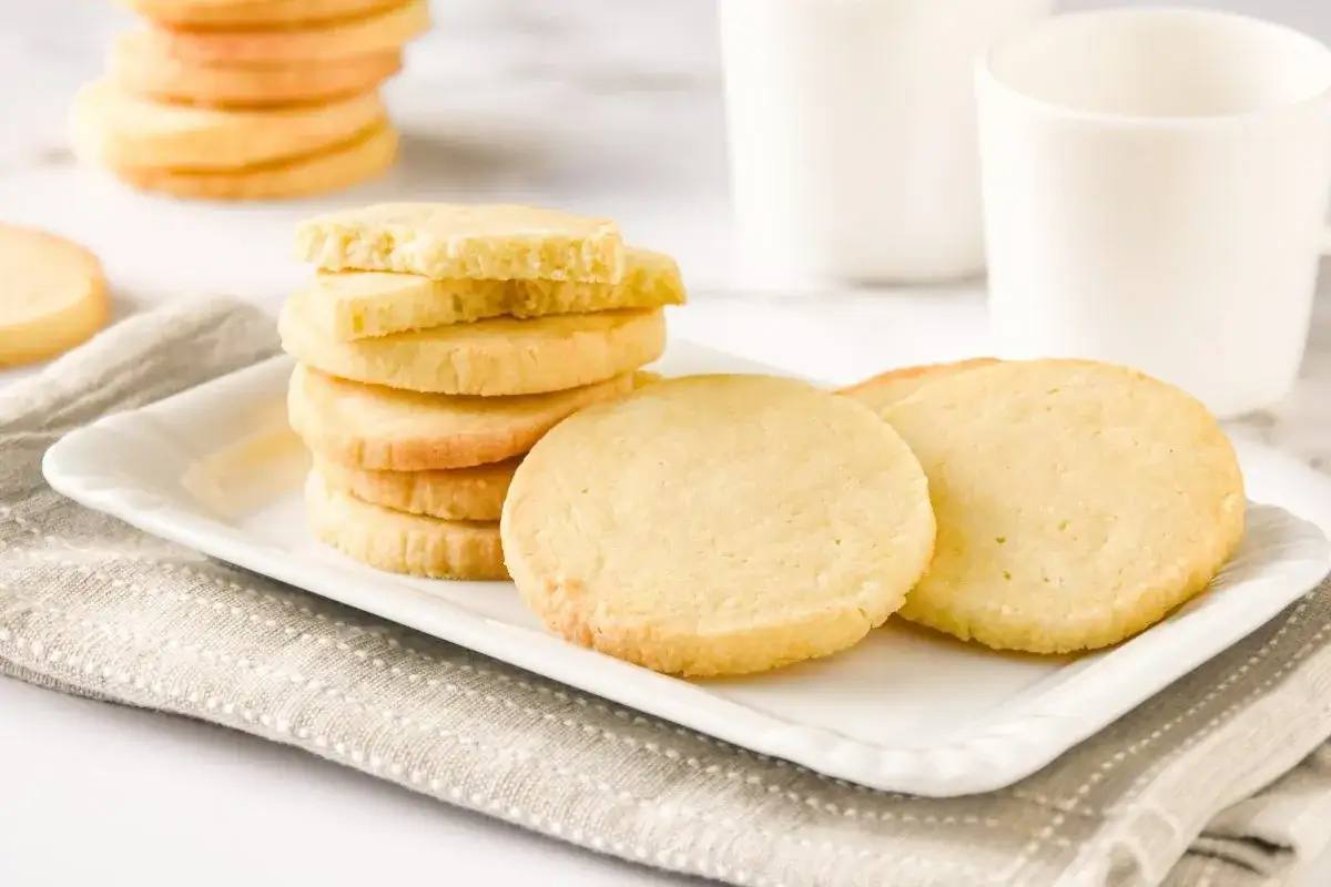 Deliciosas galletas caseras apiladas en un plato blanco, listas para disfrutar con un vaso de leche.