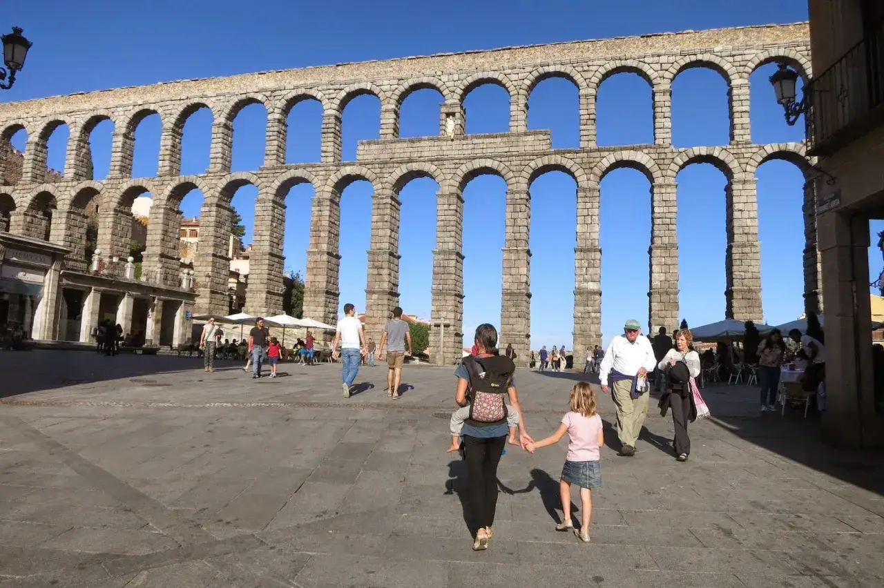 Familia pasea bajo el Acueducto de Segovia, un lugar ideal que ver en Segovia con niños.