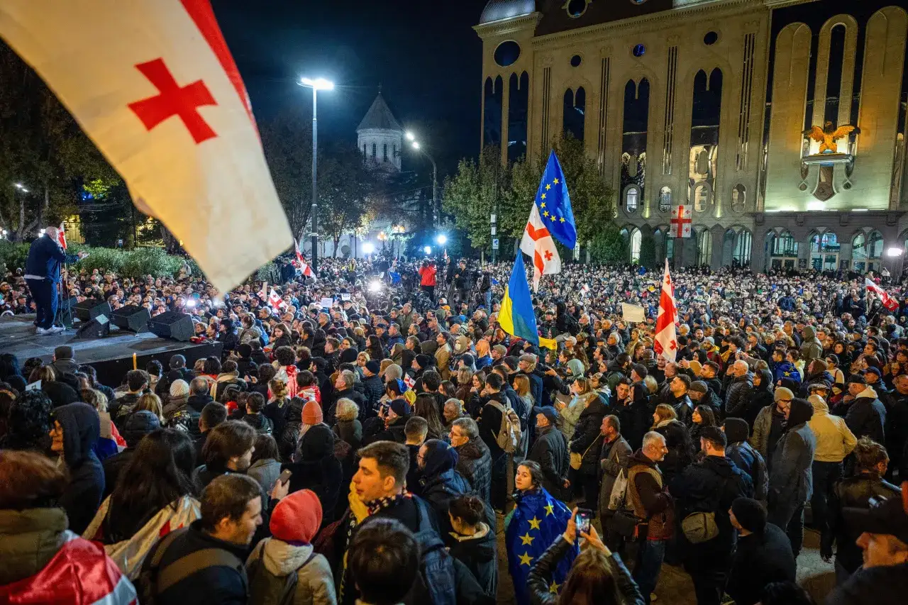 Tłum na wiecu w Gruzji, z flagami Gruzji i UE. Sytuacja polityczna w kraju budzi emocje.