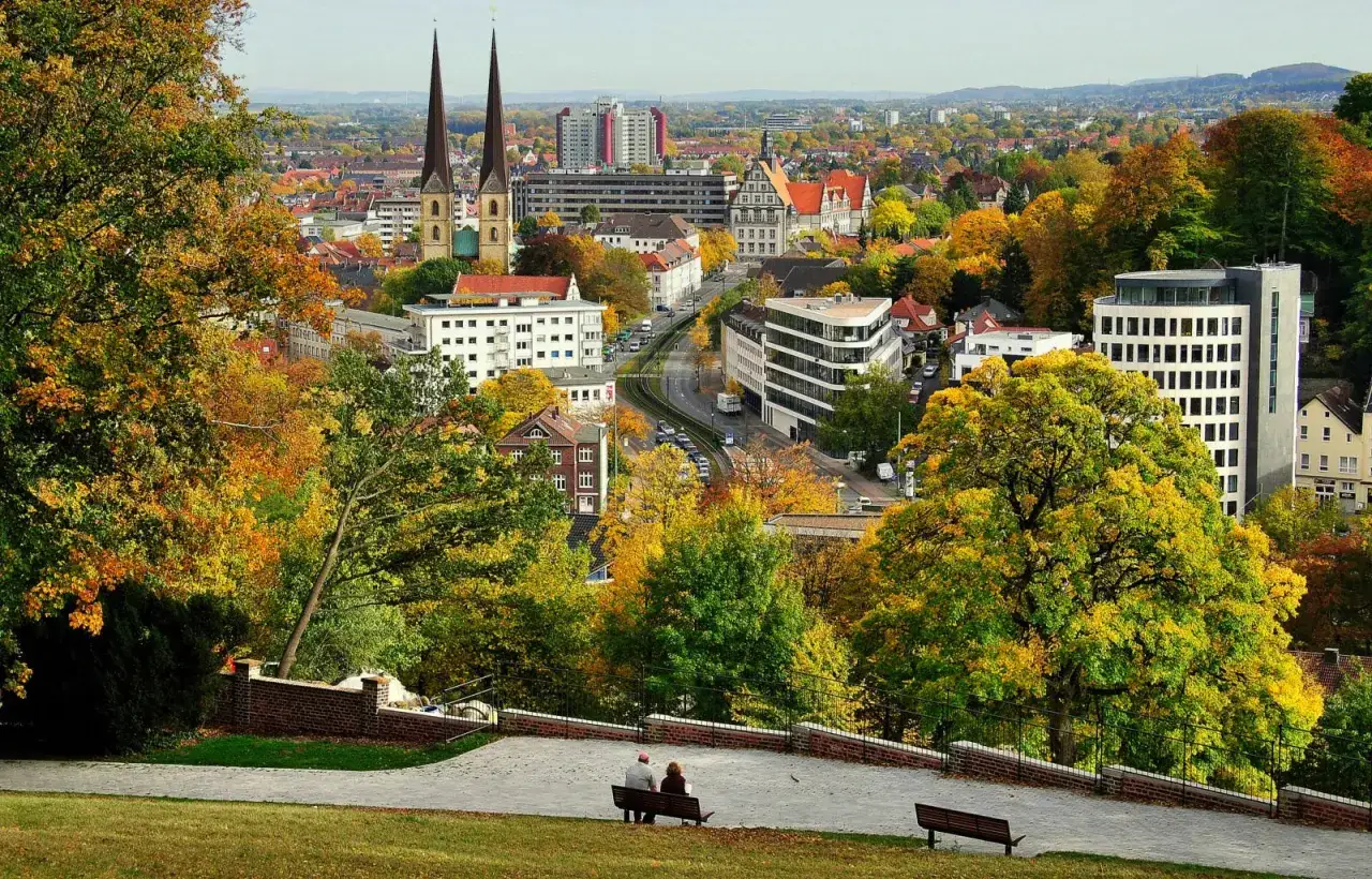 Herbstlicher Blick auf Bielefeld mit Kircht&uuml;rmen und bunten B&auml;umen. Entdecken Sie Bielefeld Geheimtipps von diesem Aussichtspunkt.