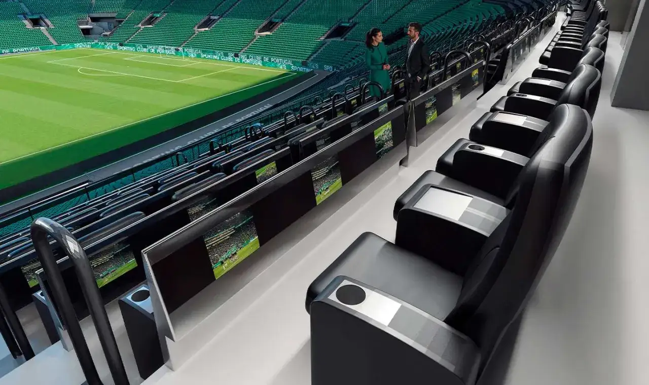 Para elegancko ubranych osób ogląda mecz na stadionie Sporting Lizbona. Widok na zieloną murawę i trybuny.