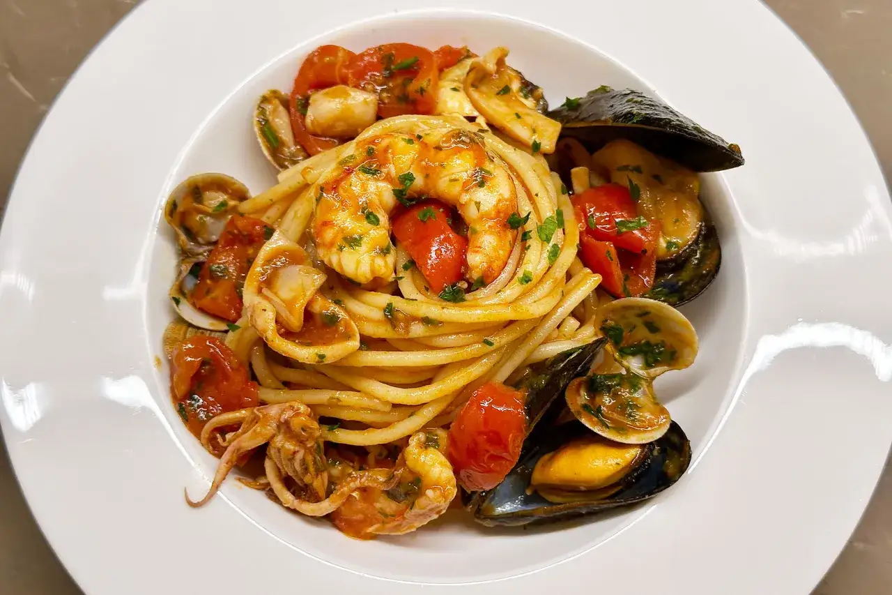 Spaghetti allo scoglio ricchi di gamberi, cozze, vongole e calamari, conditi con pomodorini freschi e prezzemolo.