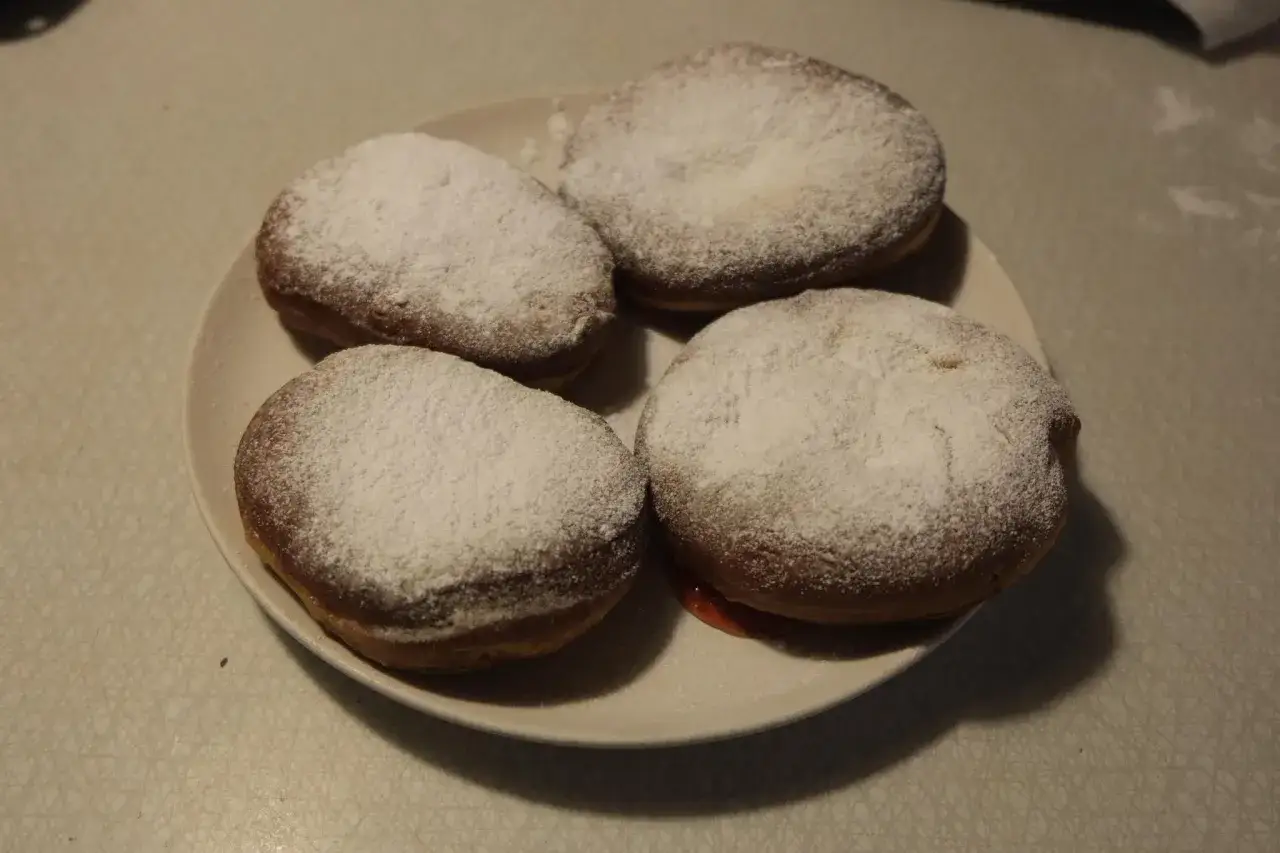 Fyra gammaldags munkar med florsocker på en tallrik. Perfekt för ett gammaldags munkar recept.