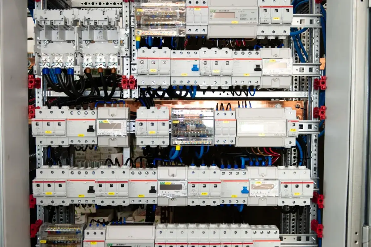 Panel elektryczny z licznymi wyłącznikami i przewodami. Prawidłowy dobór przewodów elektrycznych jest kluczowy dla bezpieczeństwa instalacji.