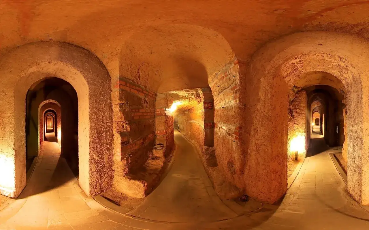 Un labirinto di corridoi illuminati, con archi in mattoni e terra battuta, che si estendono in profondit&agrave;. Un viaggio nelle misteriose grotte sotterranee.