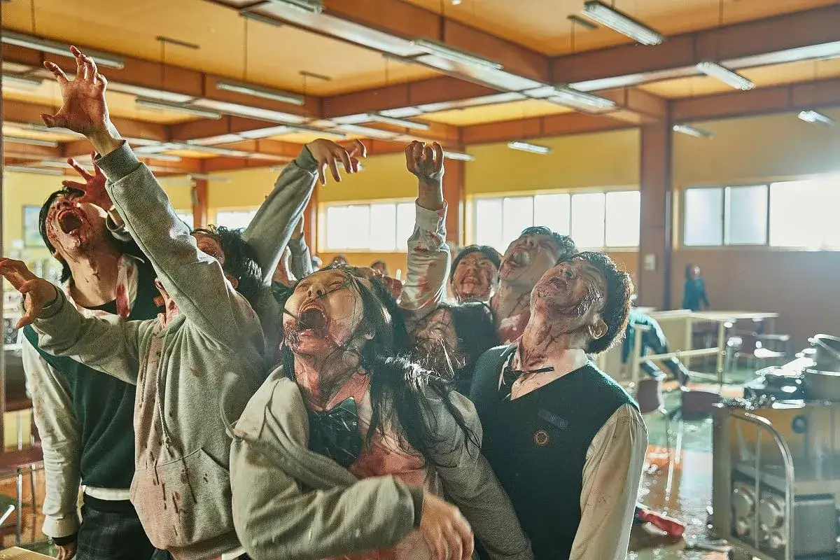Grupa przerażonych uczniów, teraz zombie, z otwartymi ustami i zakrwawionymi twarzami, krzyczy w szkolnej klasie. Wygląda na to, że all of us are dead.