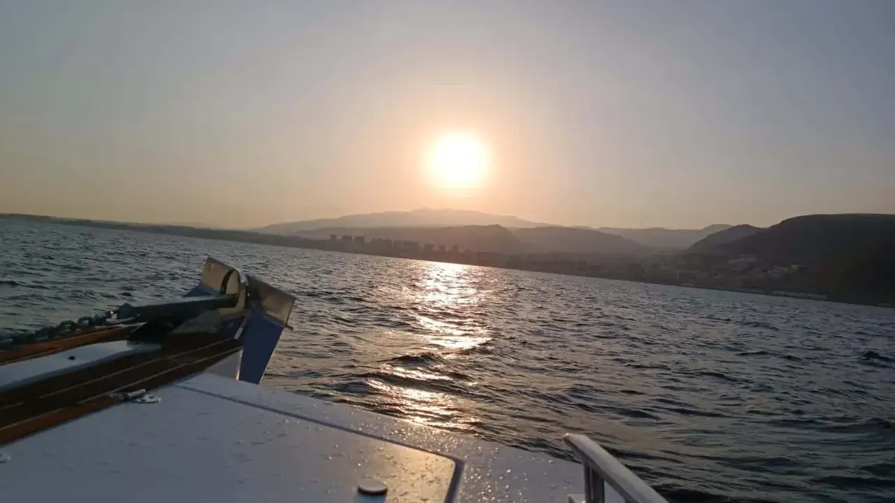 Atardecer en barco, ideal para ver qué ver en Aguadulce. El sol se refleja en el mar mientras la costa se dibuja al fondo.