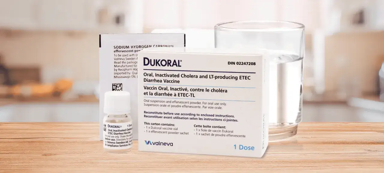 Dukoral, ett vaccin mot turistdiarré, med ett glas vatten och ett pulverpaket.