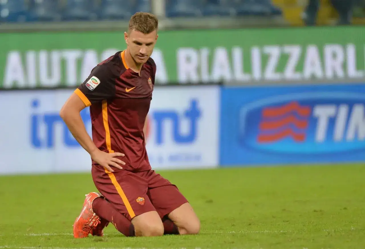 Piłkarz AS Roma klęczy na boisku, smutny po przegranym meczu. Bośnia i Hercegowina kibicuje mu.