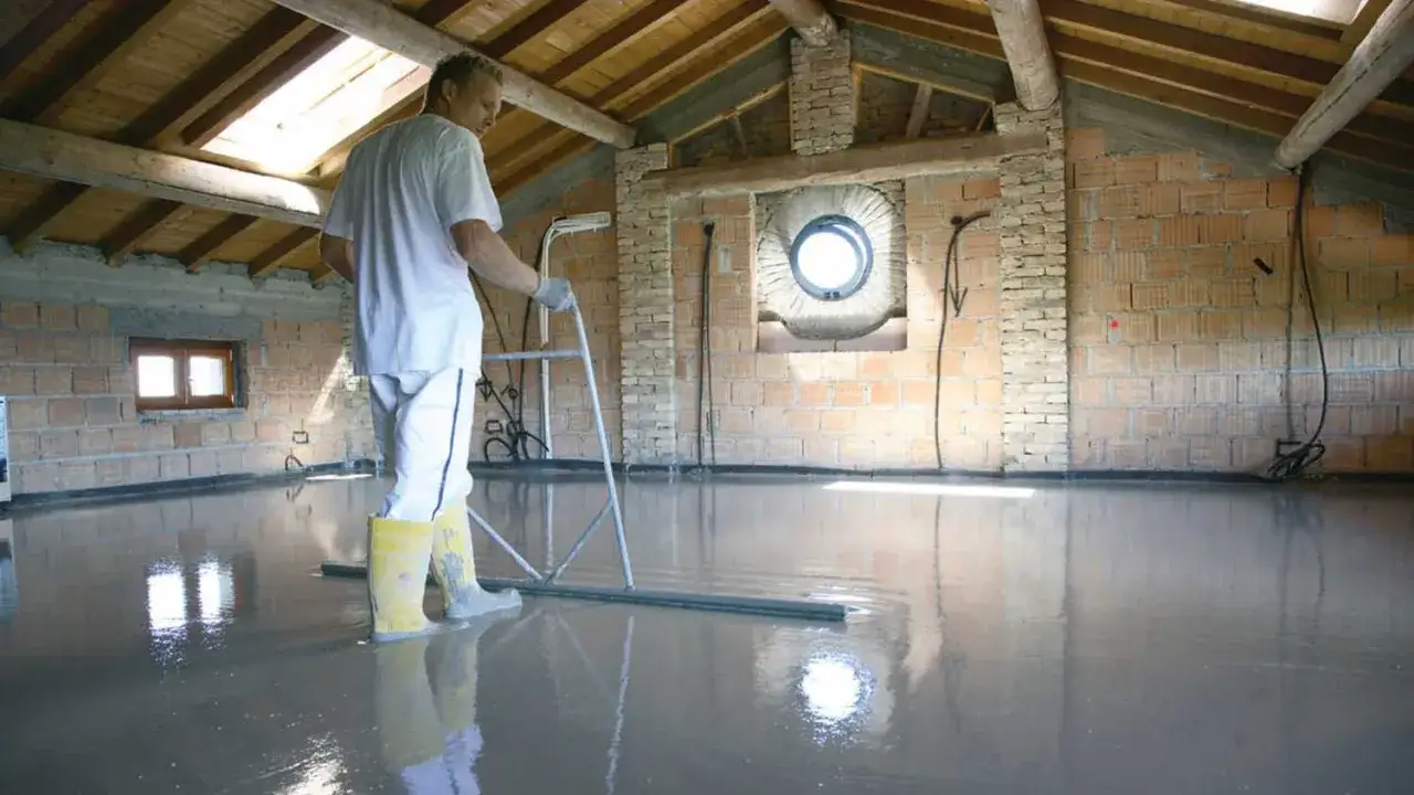 Operaio stende il massetto per un solaio a margherita, creando una superficie liscia e riflettente.