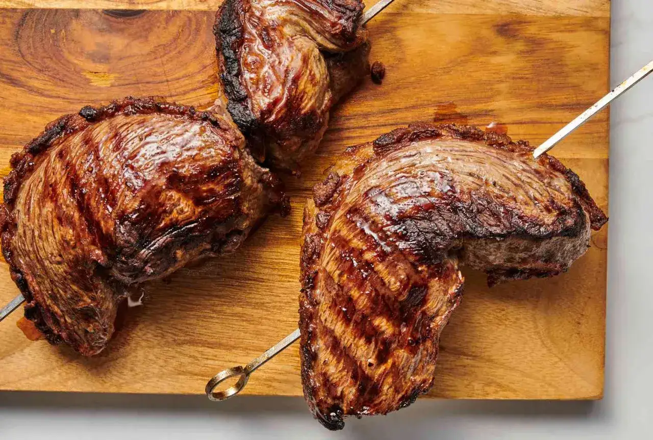 Grillad picanha p&aring; ett tr&auml;fat, perfekt f&ouml;r ett picanha recept. K&ouml;ttet &auml;r saftigt med fin grillr&auml;nder.