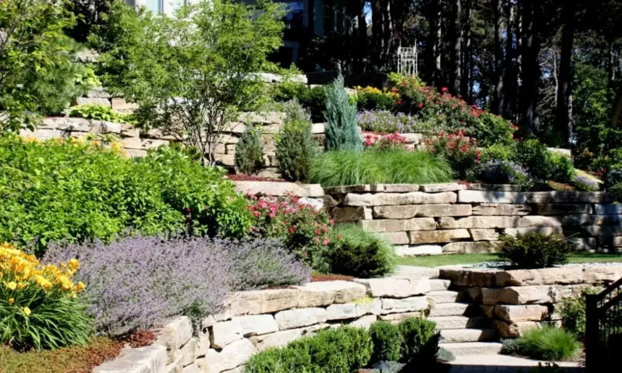 Giardini in pendenza idee: terrazzamenti in pietra con fiori colorati e vegetazione rigogliosa creano un paesaggio naturale e armonioso.