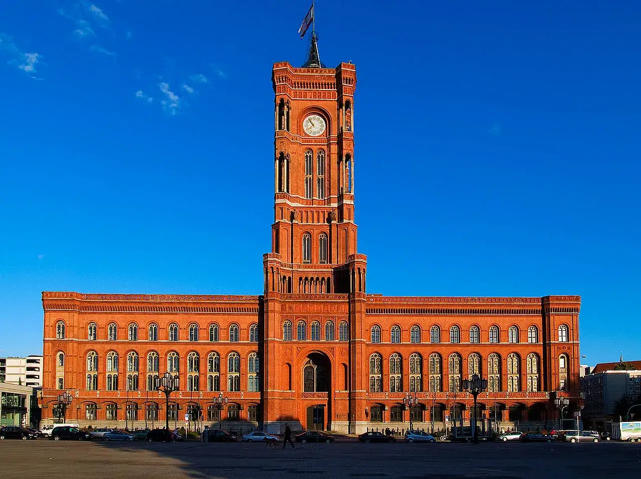 Das Rote Rathaus Berlin, ein imposantes Backsteingebäude mit einem markanten Turm, ragt unter einem strahlend blauen Himmel auf.