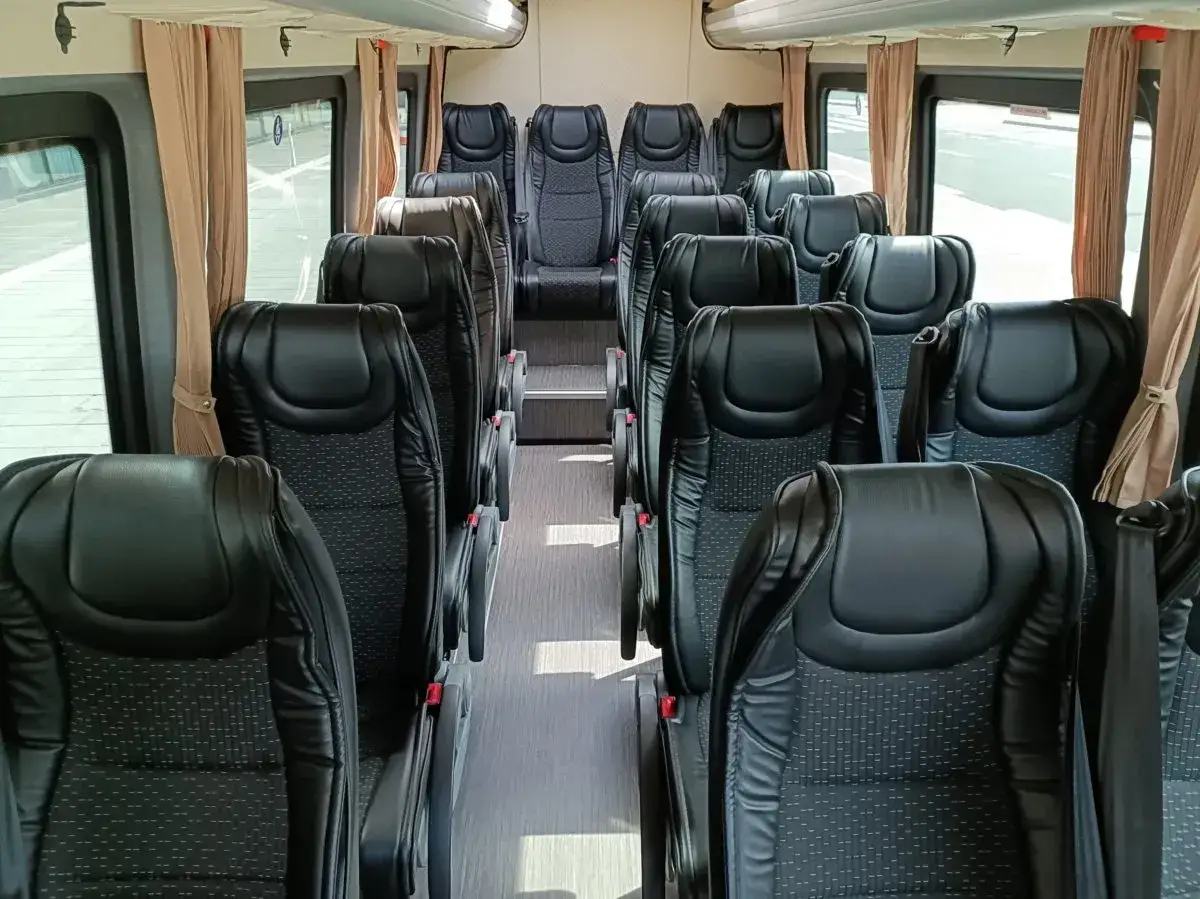 Wnętrze busa z rzędami czarnych, wygodnych foteli. Idealne na wycieczkę zorganizowaną z okazji Mikołajek w Warszawie.