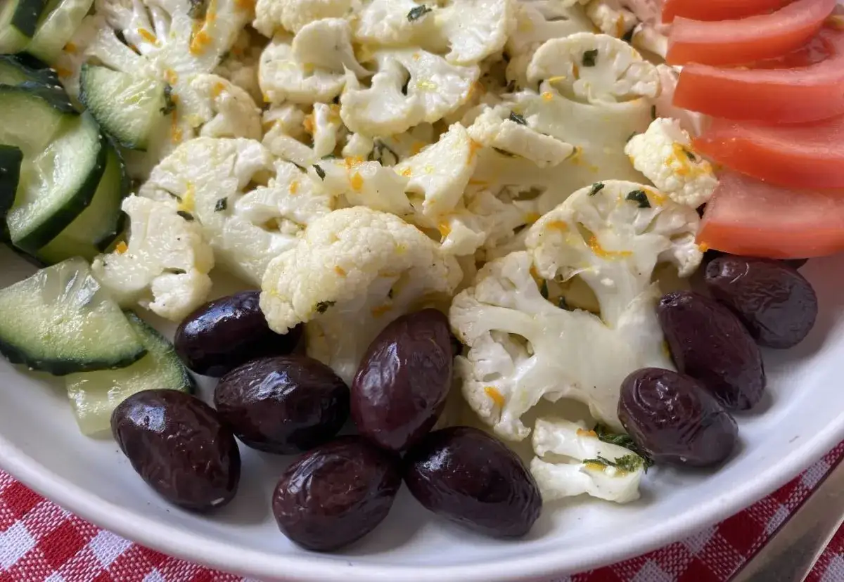 Deliciosa ensalada de coliflor con aceitunas negras, rodajas de pepino y tomate. Un plato fresco y saludable.