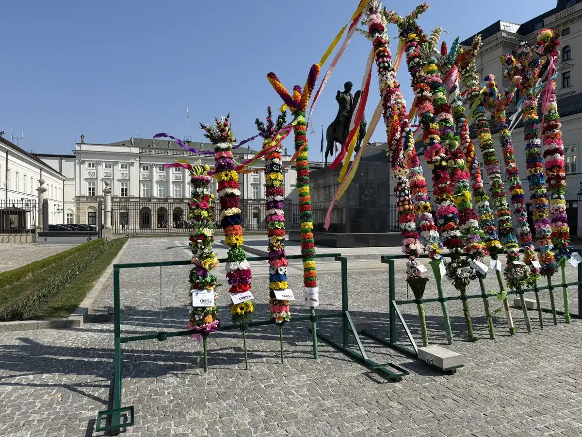 Kolorowe palmy wielkanocne ozdobione kwiatami i wstążkami stoją przed Pałacem Prezydenckim. Tradycja na niedzielę palmową.