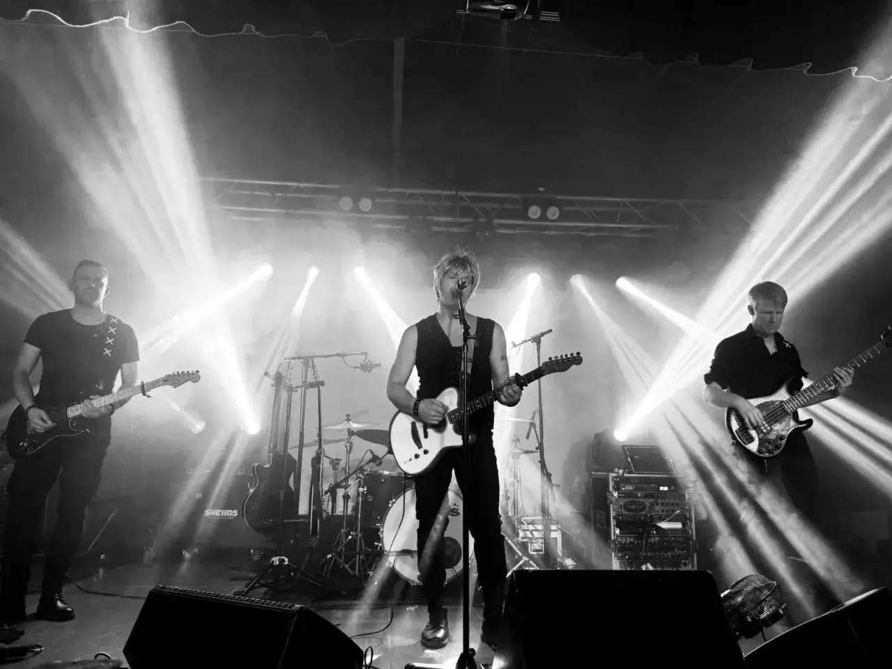 Un groupe francais rock en pleine action, éclairé par des projecteurs intenses sur scène.