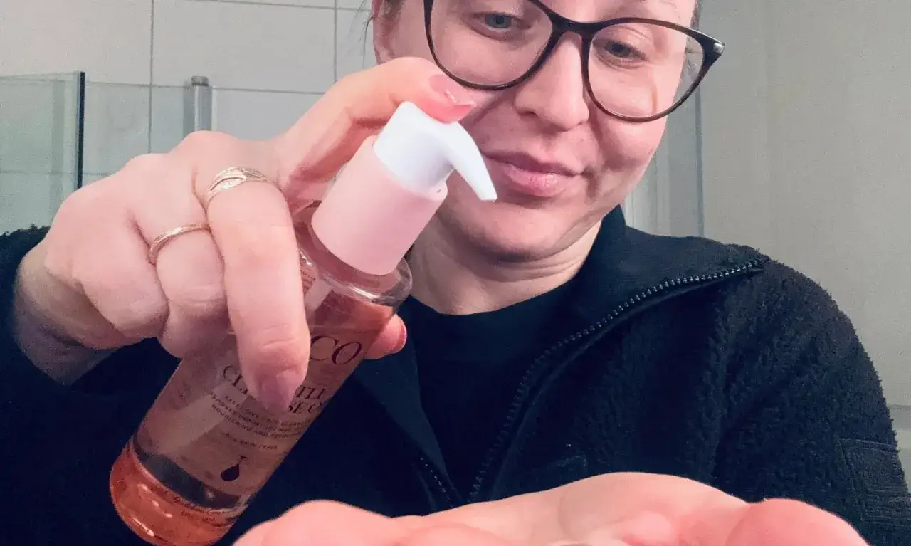 Kvinna med glas&ouml;gon pumpar olja f&ouml;r dubbelreng&ouml;ring i handen.