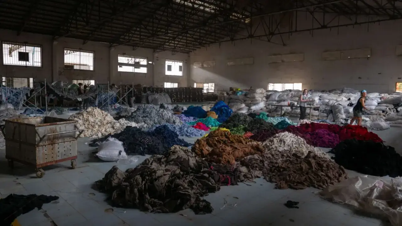 Montón de retazos de tela de colores en un almacén, reflejo de que es la fast fashion y su impacto.