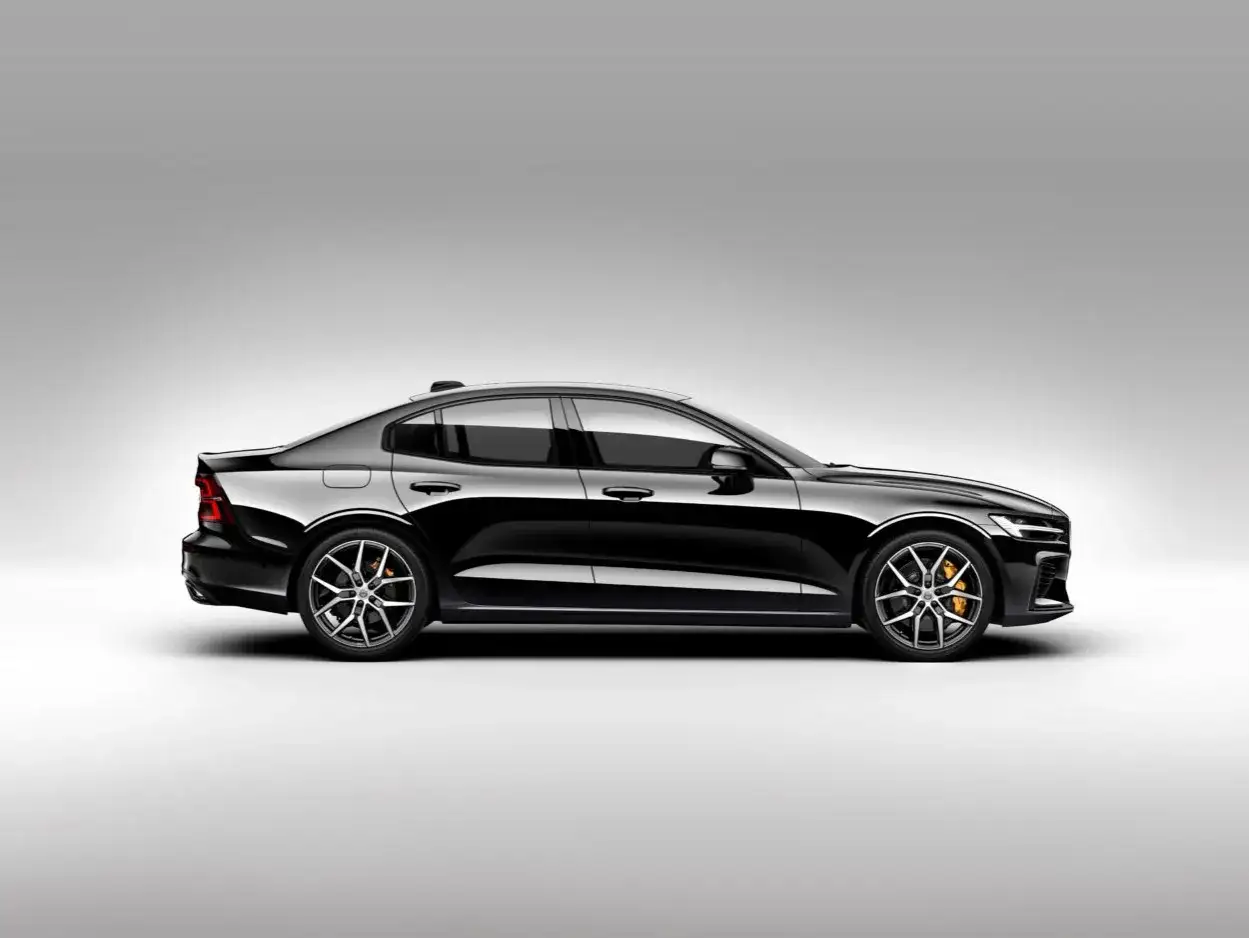 Elegancki, czarny Volvo S60 V8 z pomarańczowymi zaciskami hamulcowymi na tle jasnej przestrzeni.