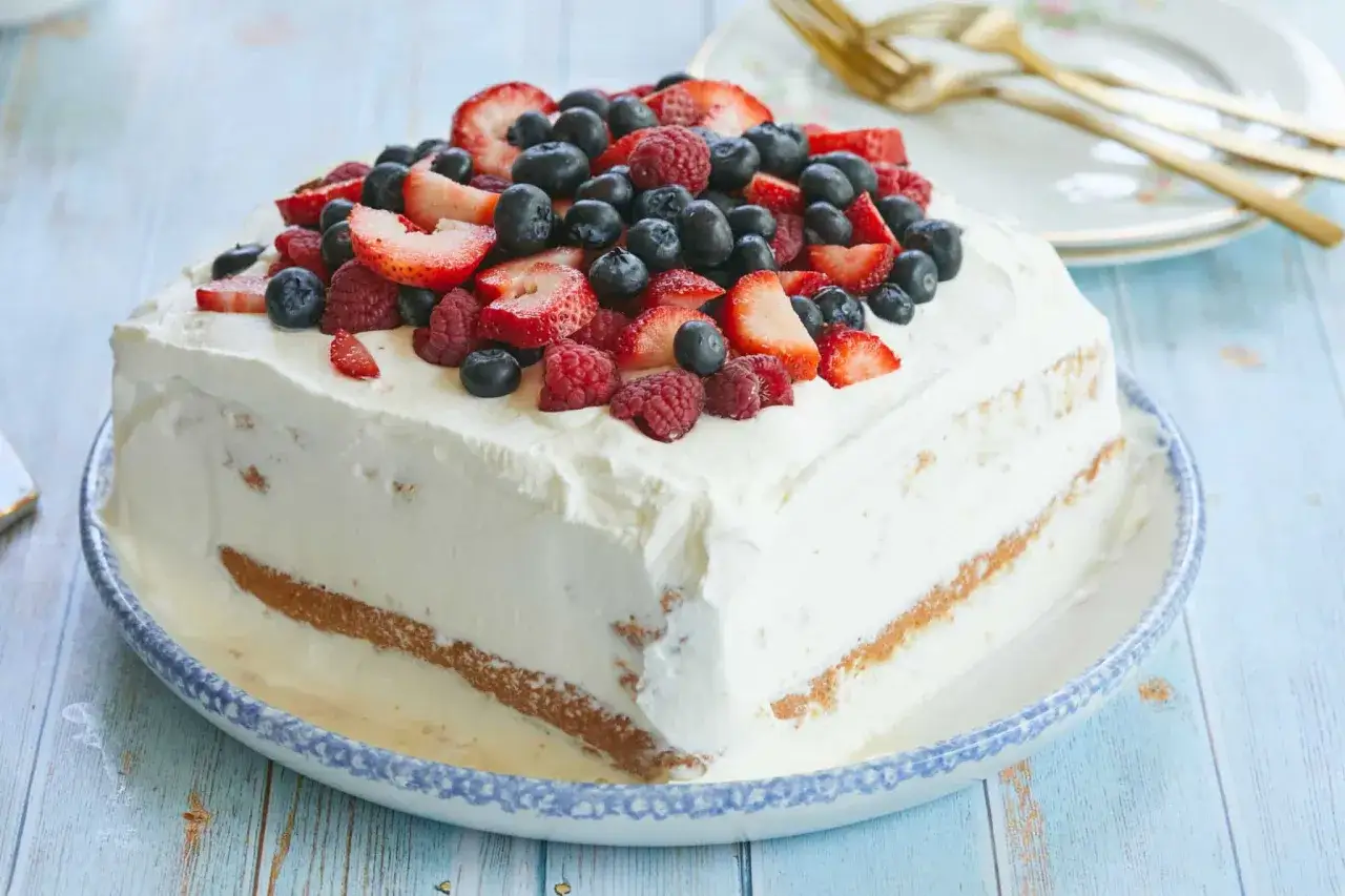 En kr&auml;mig tres leches-t&aring;rta toppad med f&auml;rska b&auml;r, perfekt f&ouml;r en sommarfest.