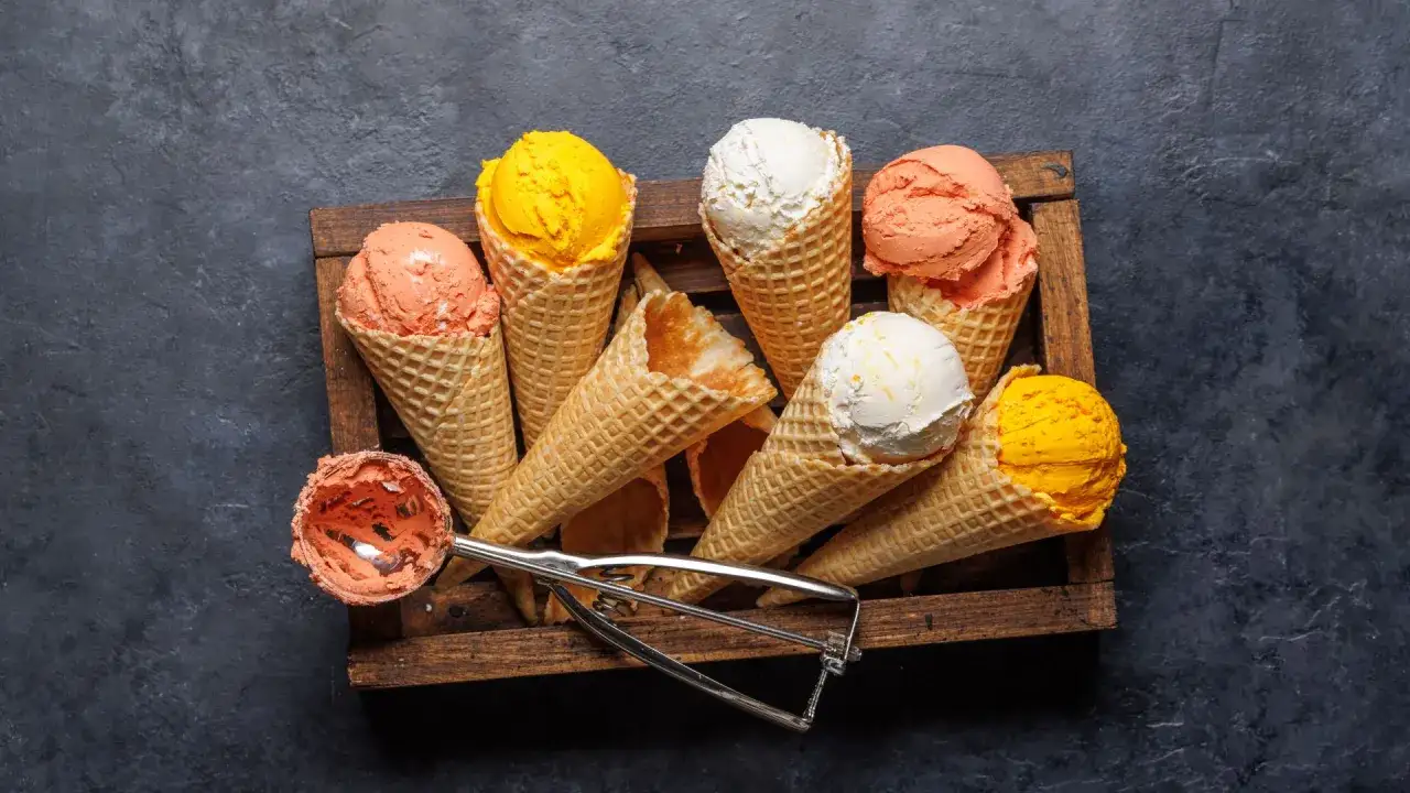 Una bandeja de madera con varios conos de helado de naranja, blanco y amarillo. ¿Quién inventó el helado? ¡Quizás ellos!