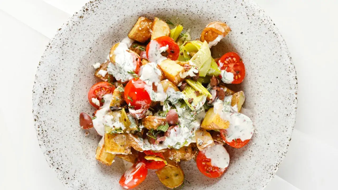Ensalada de patatas asadas con tomates cherry, puerro y aderezo cremoso. Una de las muchas recetas con patatas que te encantarán.