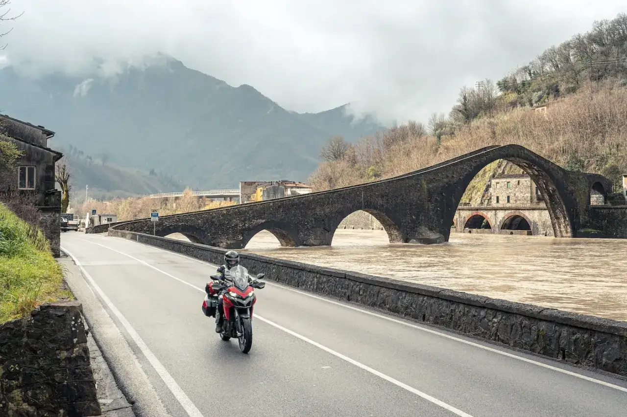 Un motociclista esplora i borghi pi&ugrave; belli della Toscana, attraversando il Ponte del Diavolo con la sua moto.
