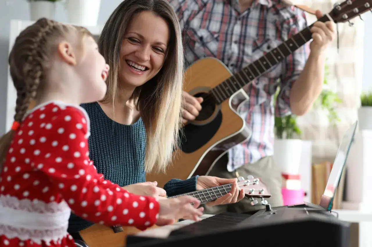 Rodzina gra na instrumentach, tworząc piosenki o mamie. Radość i muzyka wypełniają dom.
