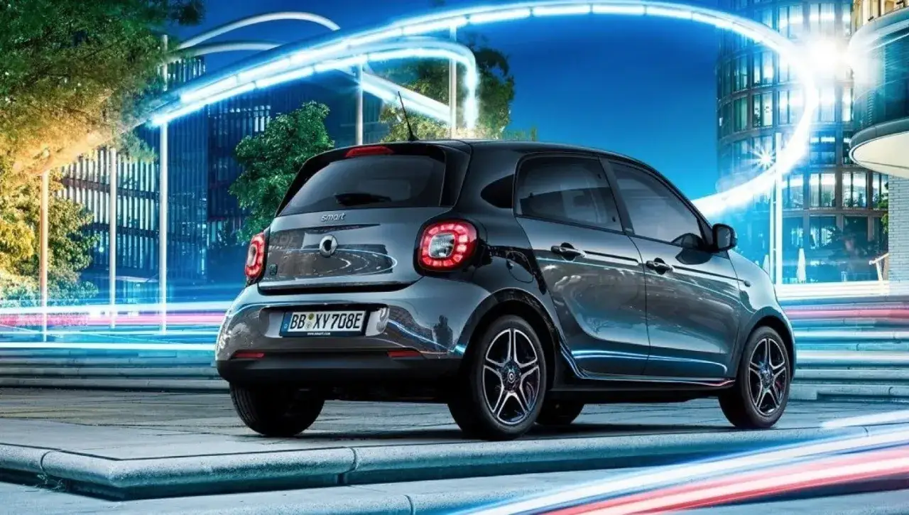 City car 5 posti grigia parcheggiata in una città moderna con luci al neon e architettura futuristica.