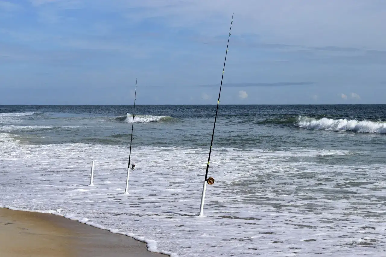Drei Angelruten stehen im Wasser f&uuml;r Nordsee Angeln vom Ufer. Die Wellen brechen am Strand.